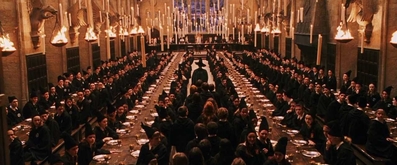 What is Mise-en-Scéne? Definition, Elements & Examples 4 Hogwarts students seated in rows under floating candles in the Great Hall, with a central figure walking toward the staff table.