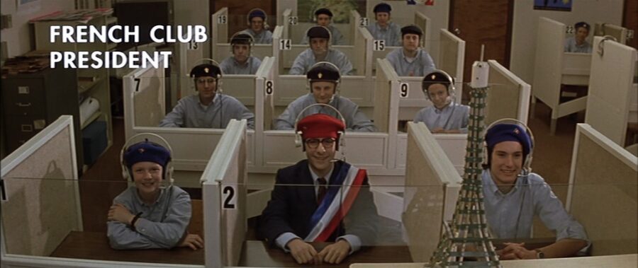 What is The Hollywood Model (aka "Berettermodellen")? Definition & Examples 6 Students in berets sit at language lab desks labeled with numbers; one in front wears a sash labeled “French Club President”