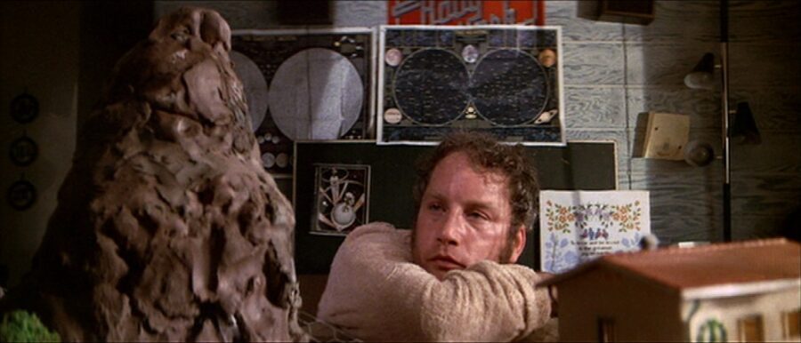 30 Films Every Budding Film Student Should Watch & Why 21 A man leans on his arm, staring at a large clay model of a mountain inside his home.