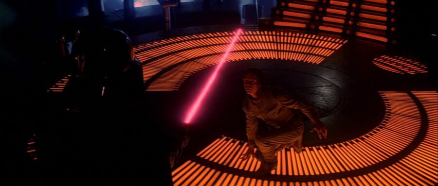 30 Films Every Budding Film Student Should Watch & Why 25 Luke Skywalker crouches defensively as Darth Vader's red lightsaber glows inches from him, set against the orange-lit floor of a futuristic chamber.