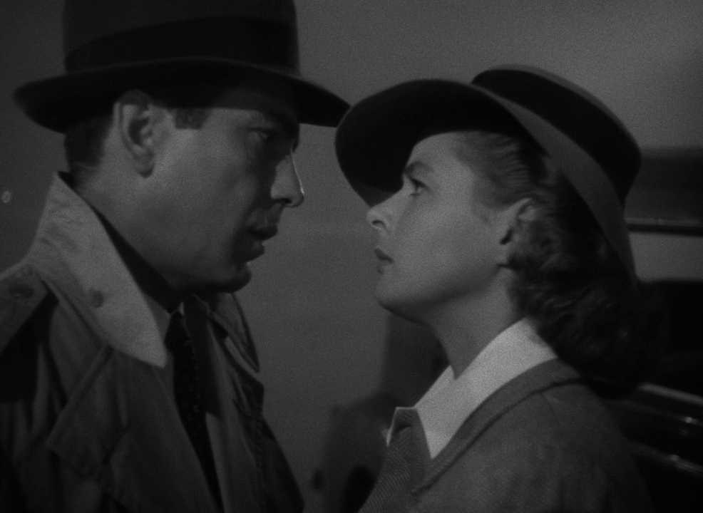 30 Films Every Budding Film Student Should Watch & Why 18 A man in a trench coat and a woman in a hat stare intensely at each other in a close-up black-and-white shot.
