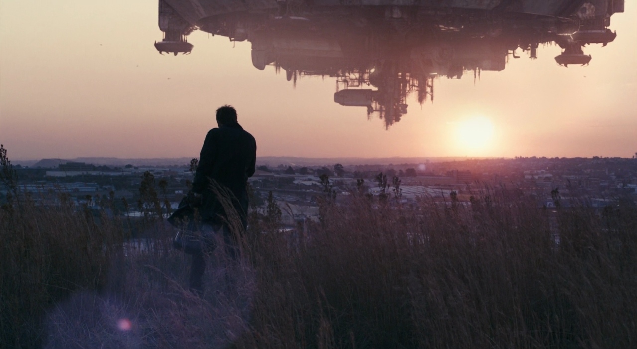 30 Films Every Budding Film Student Should Watch & Why 27 A man stands in tall grass at sunset, looking toward a massive alien ship hovering over a city.