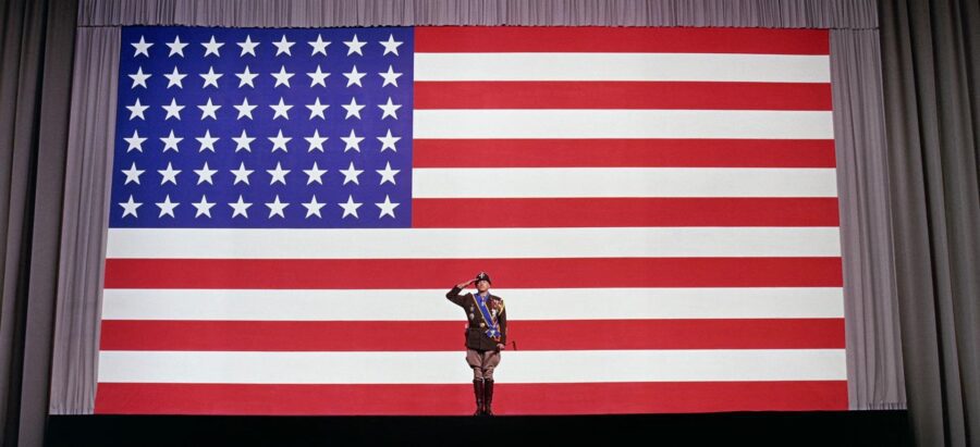 30 Films Every Budding Film Student Should Watch & Why 23 A military officer in full uniform salutes in front of a massive American flag backdrop on stage.