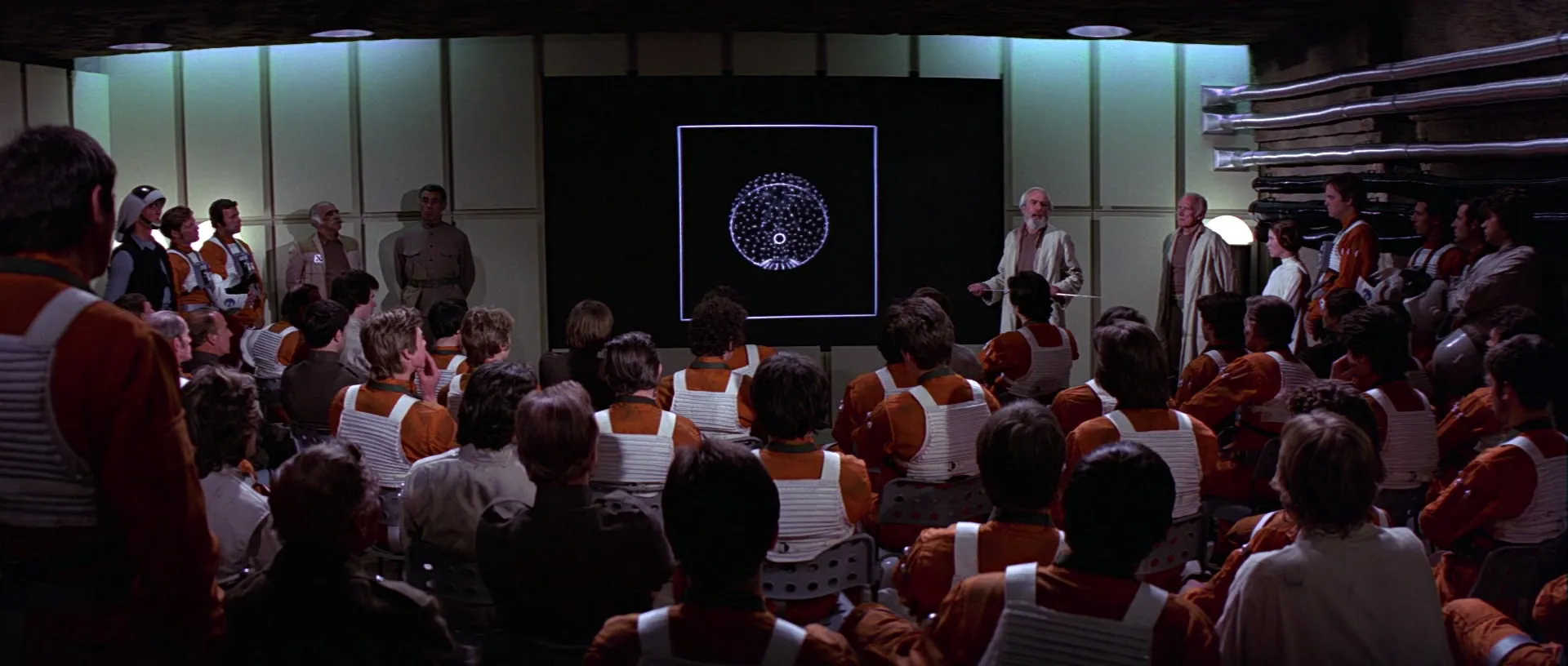 What Is A MacGuffin? Definition + Good & Bad Examples Explained 5 Rebel pilots and leaders gather around a screen showing the Death Star plans in Star Wars: A New Hope.