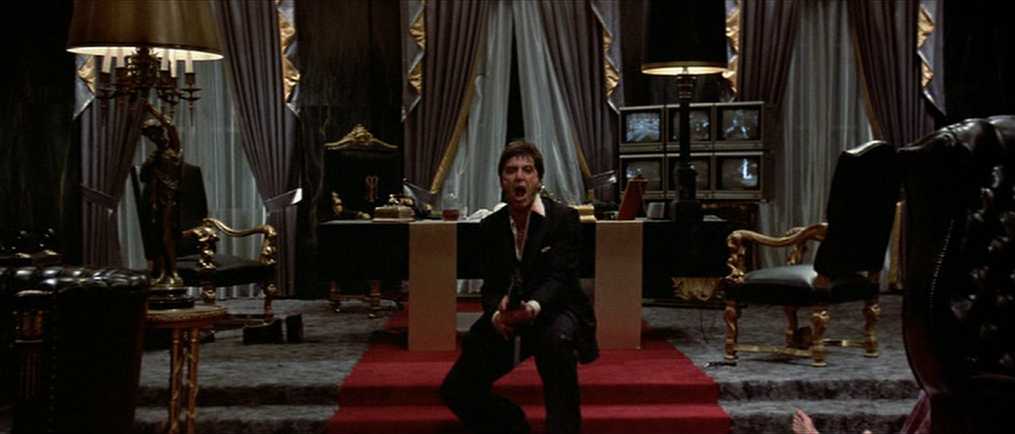 10 Best Gangster Movies of All Time For Filmmakers To Watch 3 Tony Montana stands with a gun in a lavish mansion office with red carpet and gold furniture