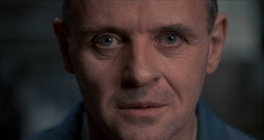 What Is an Antagonist? Meaning, Role & Film Examples 3 Hannibal Lecter stands behind glass, watching with intense calm.