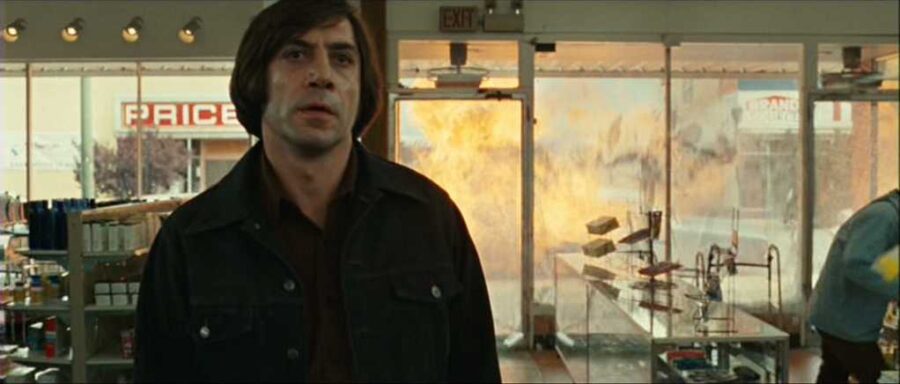 What Is an Antagonist? Meaning, Role & Film Examples 2 Anton Chigurh stands with a cold, unreadable expression, signaling a relentless threat.