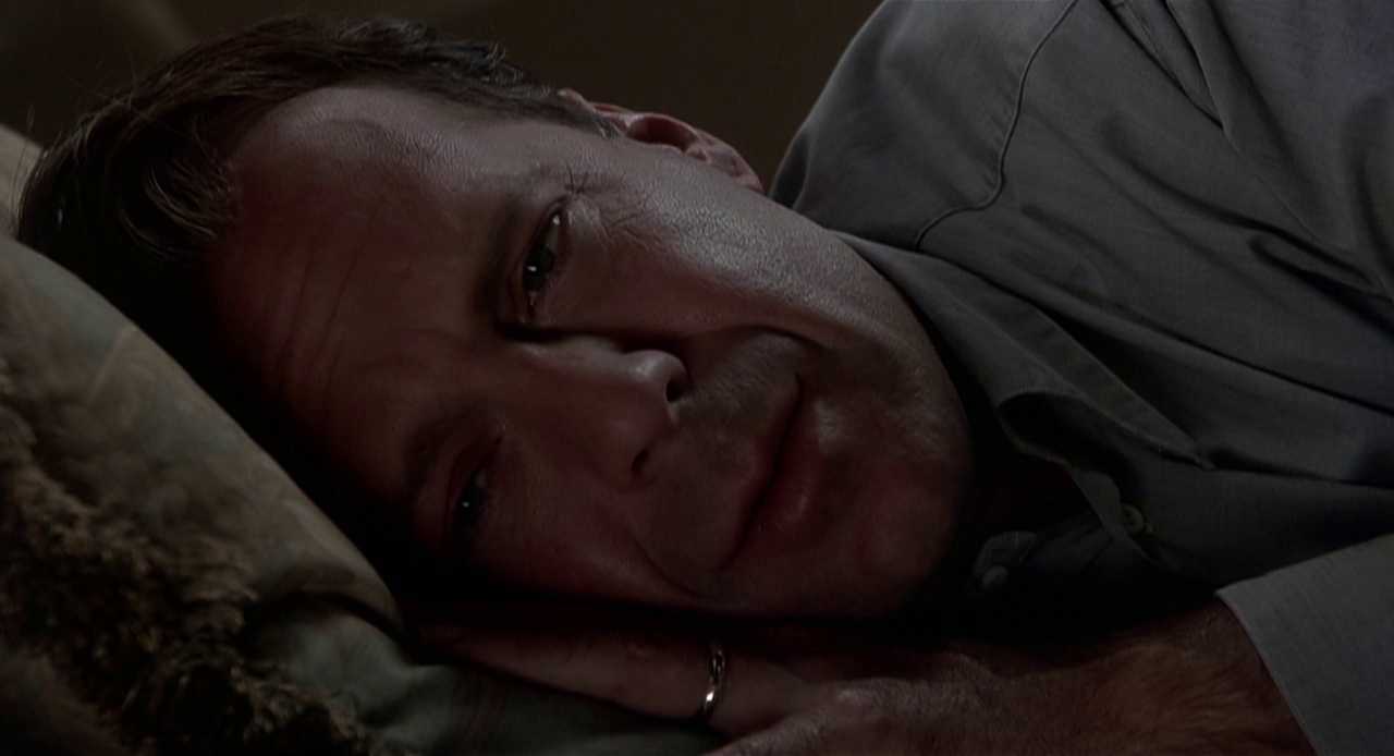 Context in Screenwriting and Film: A Complete Guide 10 A man lies on a pillow with a distant expression, partially in shadow, as he begins to understand something painful
