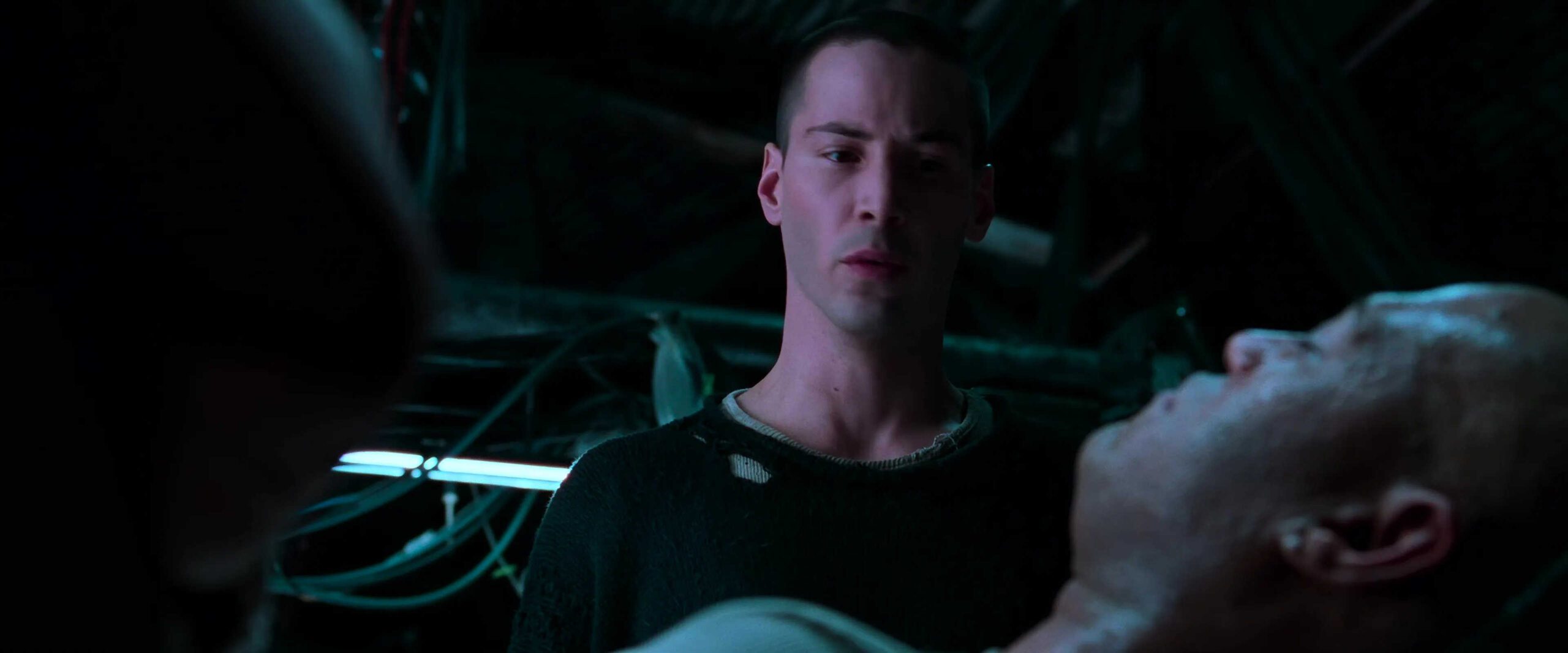 What is Campbell's Monomyth? A Hero Guide for Filmmakers 11 Neo stares at the unconscious Morpheus under cold blue lighting, his face tense and conflicted.