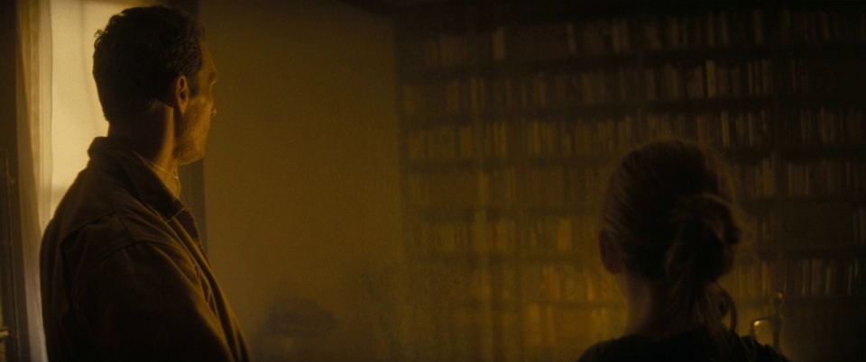 Paradox in Film: Definition, Types, and Movie Examples 3 Cooper and Murph look toward a glowing bookshelf in a dimly lit room, bathed in golden light.