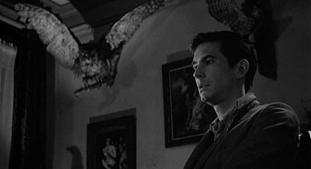 What is Repetition in Film? Definition, Meaning & Examples 5 Black-and-white shot of Norman Bates in profile indoors, with a large stuffed bird above him and framed pictures on the wall behind.