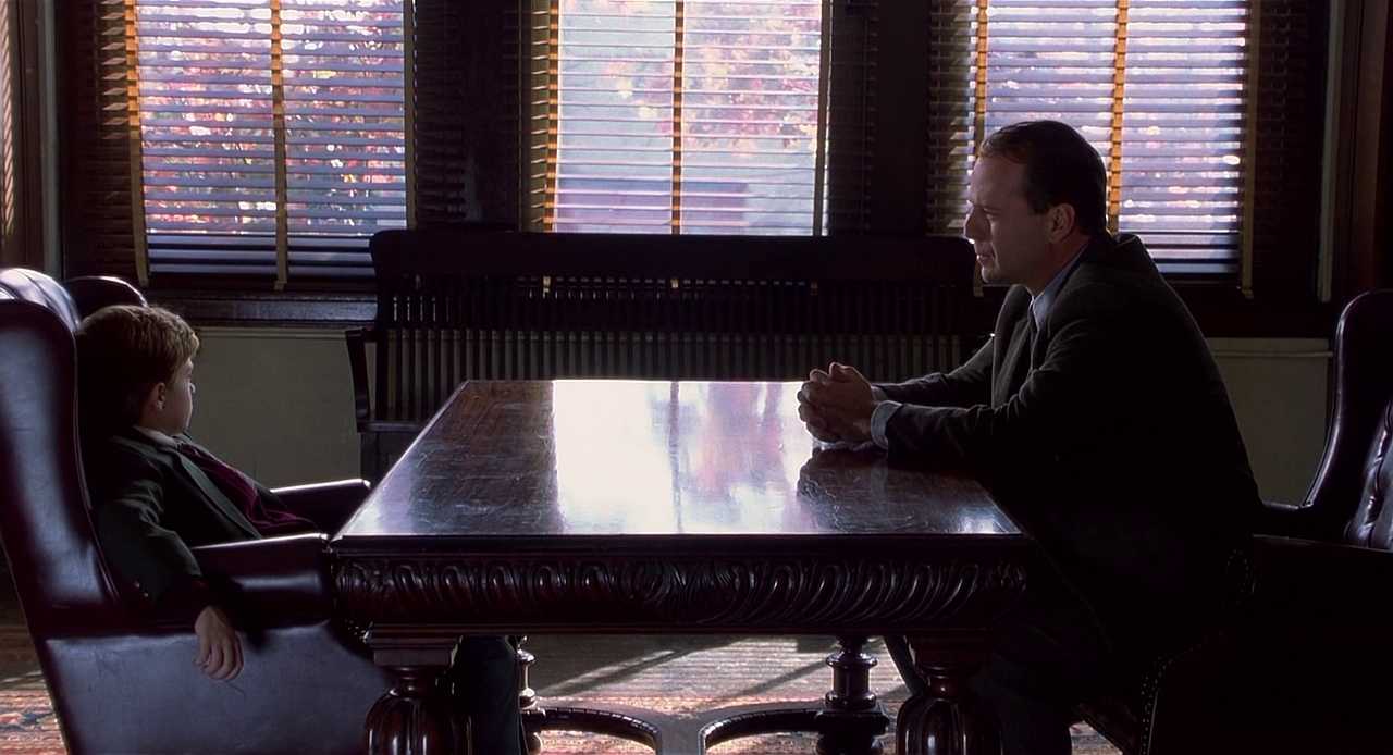 Foreshadowing in Film. Definition, Techniques & Examples 4 A man and a young boy sit across from each other at a large wooden table in a softly lit room with window blinds behind them.