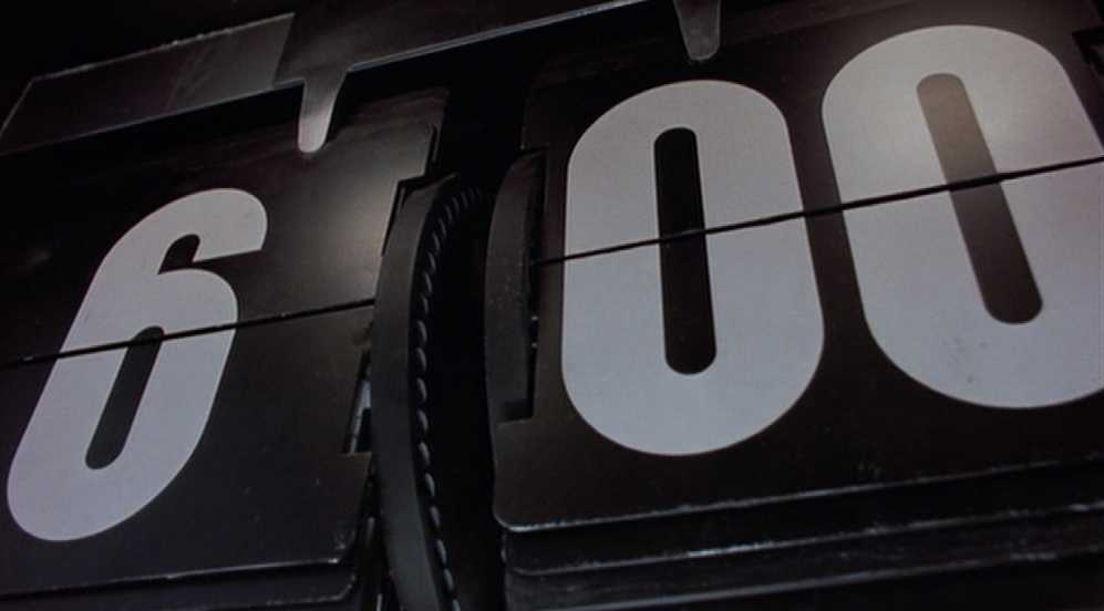 What is Repetition in Film? Definition, Meaning & Examples 2 Close-up of a black flip-style alarm clock showing 6:00 in large white numbers.