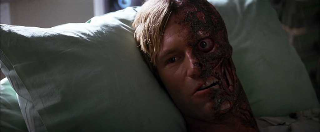 Theme in Film: Definition, Meaning, and Scene Examples 4 A close-up of a man lying on a hospital pillow, with one side of his face badly burned and scarred while the other side is intact, staring forward.