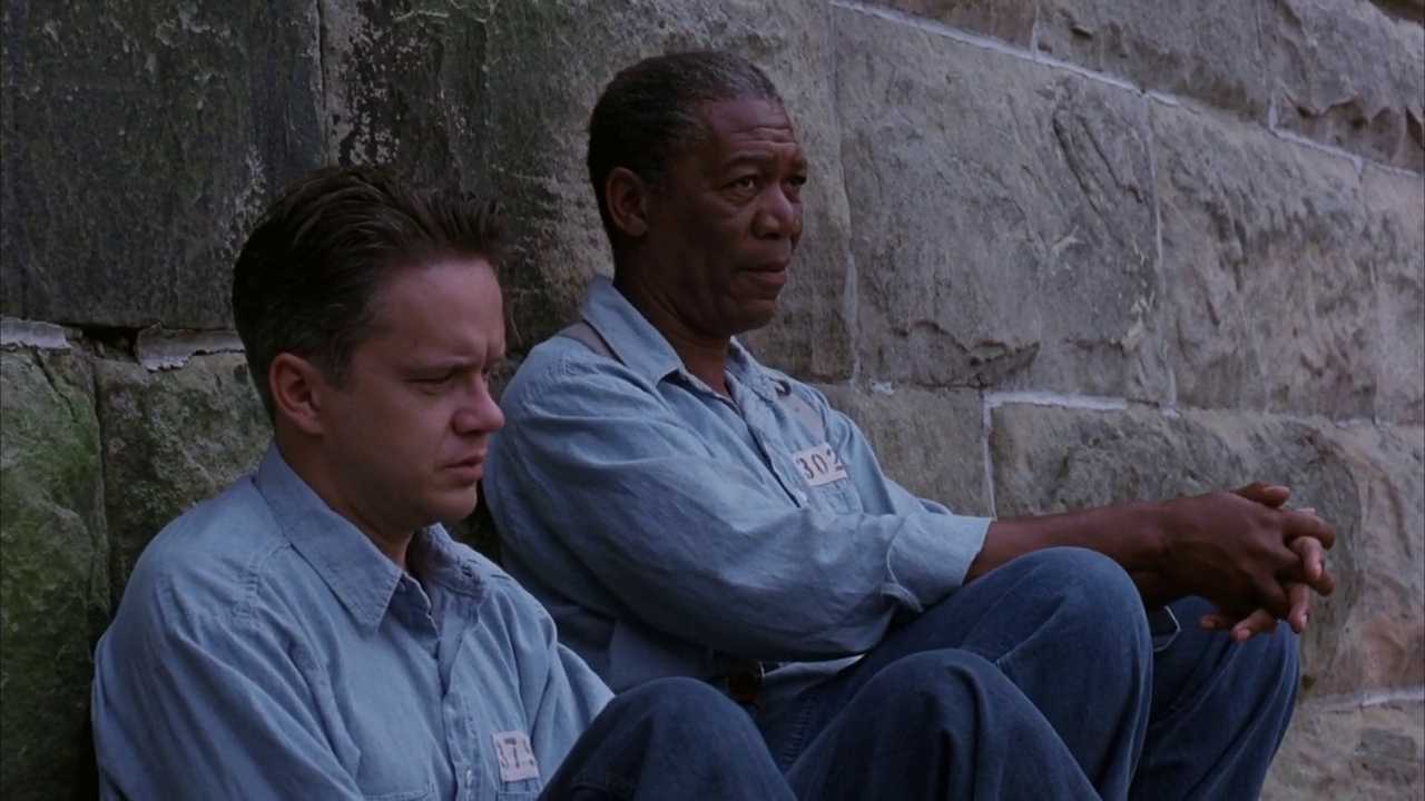 What is a Narrative in Film? Meaning, Definition & Structure Examples. 4 Two inmates in light blue prison shirts sit on the ground against a stone wall, looking off to the side during yard time.