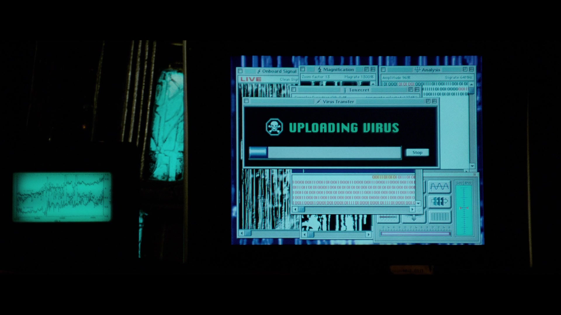 Deus ex Machina in Film & Literature. Definition & Examples. 2 Close-up of a computer monitor showing “UPLOADING VIRUS” with a progress bar and stacked technical windows and code.