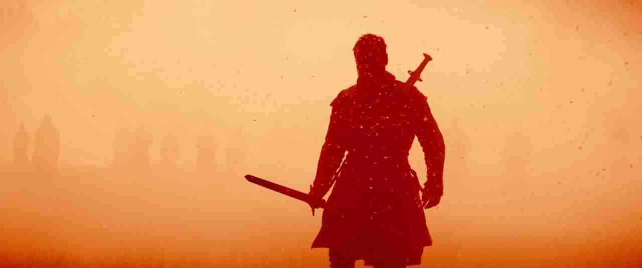Macbeth (2015) hamartia example image A warrior stands in silhouette holding a sword in a hazy orange landscape.