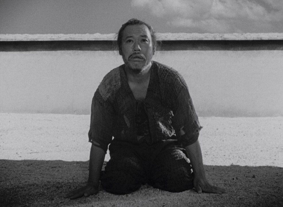 What is a Narrative in Film? Meaning, Definition & Structure Examples. 12 A black-and-white shot of a man kneeling on the ground outdoors, looking upward with a tense expression, with a low wall and sky behind him.