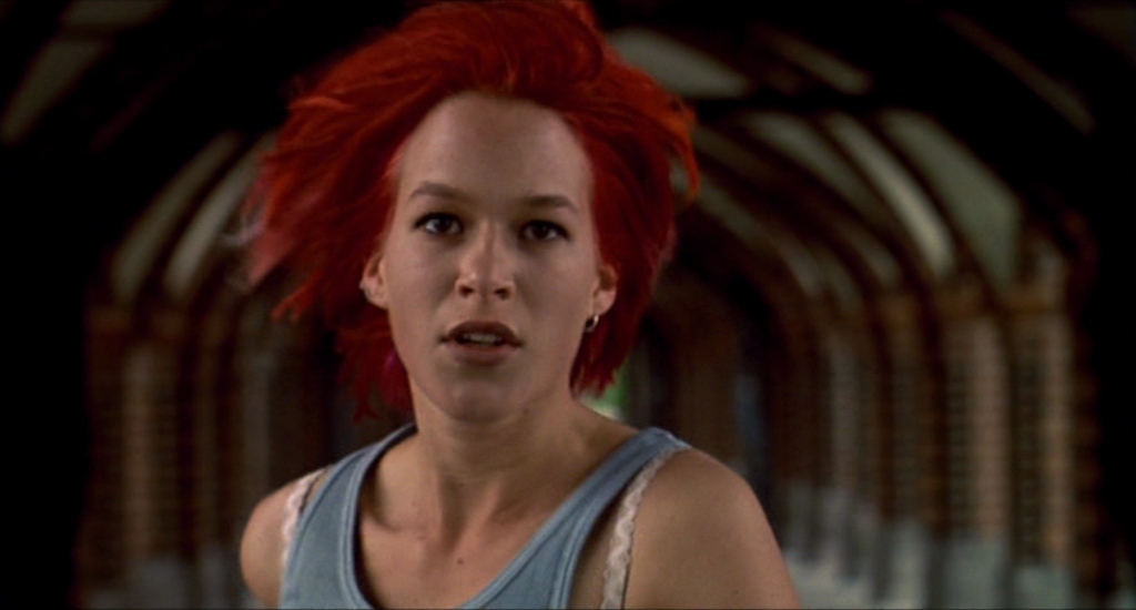 What is Repetition in Film? Definition, Meaning & Examples 4 Close-up of a woman with bright red hair running toward the camera inside a long tunnel, with the background blurred by motion.