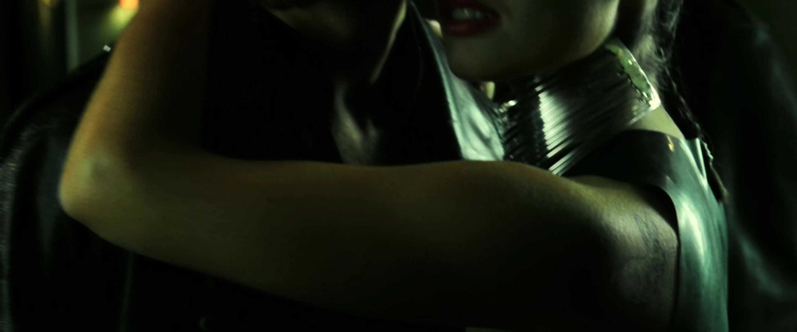 What is Allusion in Film? Meaning, Definition & Examples 3 Close-up of a woman’s arm wrapped around Neo, showing a white rabbit tattoo on her shoulder in a dim, green-lit scene.