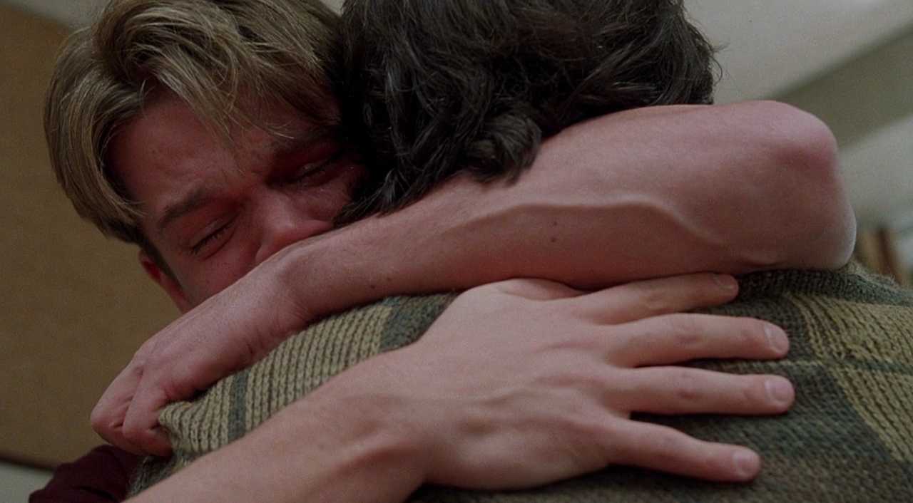 Good Will Hunting still: vulnerability and repair Two men hug tightly in close-up, and one of them has tears in his eyes.