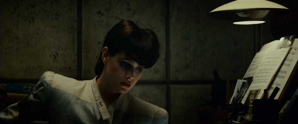 What is Tech Noir? Film Noir meets Dystopia. 5 Rachael sits alone at a piano under a lamp, looking down with tension in Blade Runner (1982)