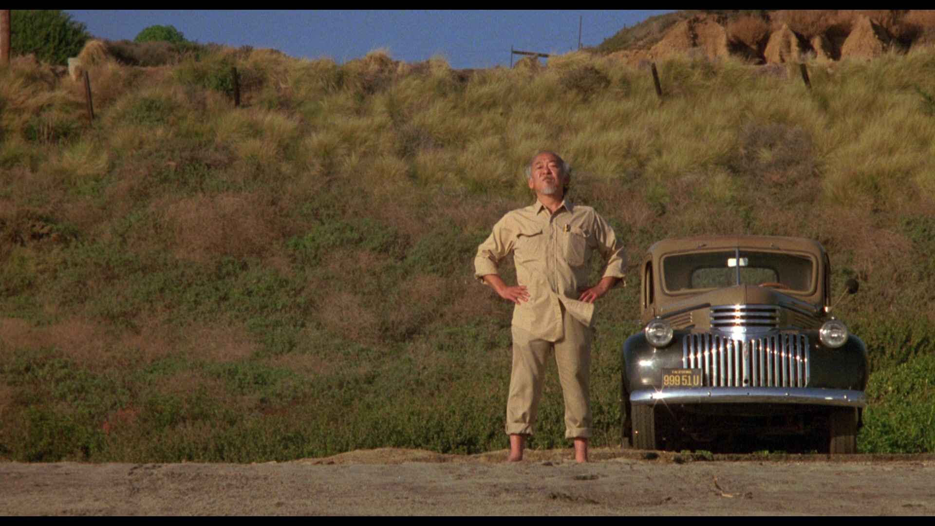 What Is a Stock Character? Definition & Film Examples 5 Mr. Miyagi stands barefoot with his hands on his hips beside an old truck in a sunny outdoor field.