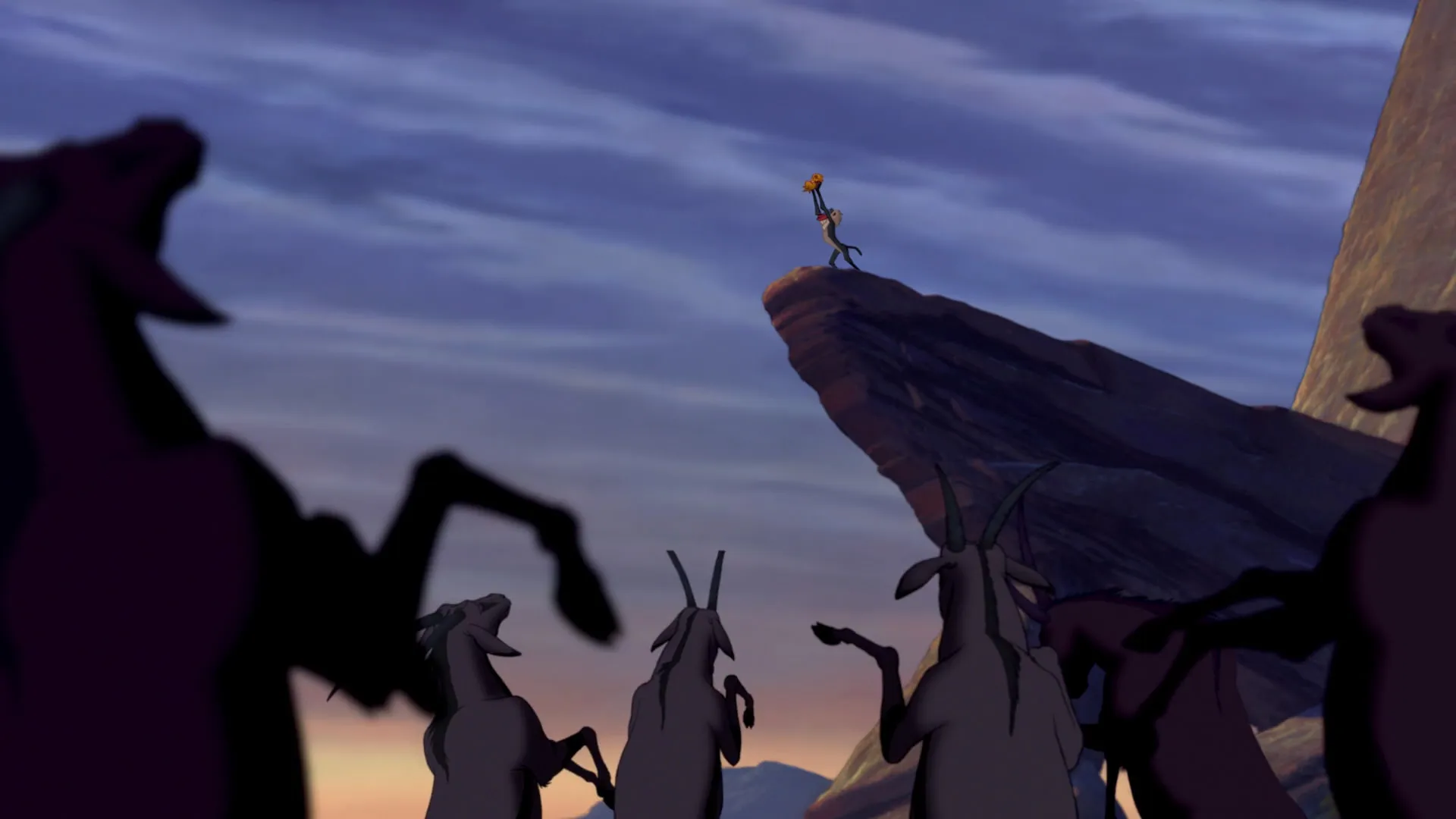 What Is a Character Arc? Definition, Stages & Film Examples 2 Rafiki holds baby Simba up on Pride Rock at sunrise while animals gather below in a wide scene.