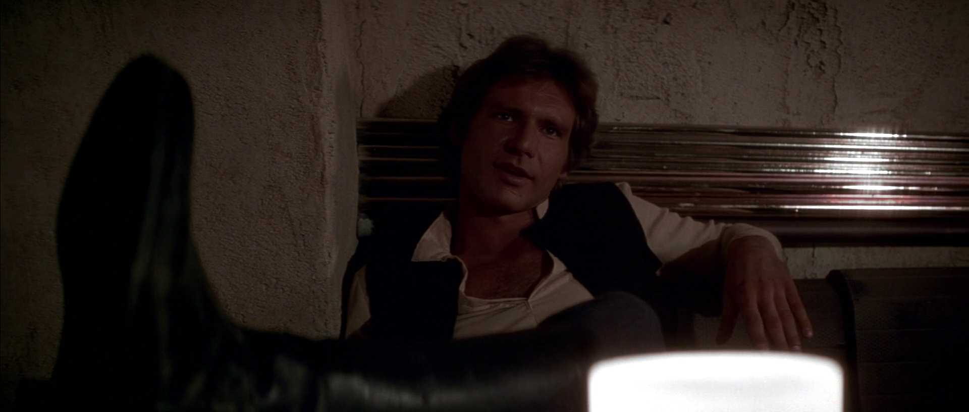 What is a Tritagonist? Definition & Film Examples 5 Han Solo reclines in a dim cantina booth, looking off screen with one arm draped over the seat.