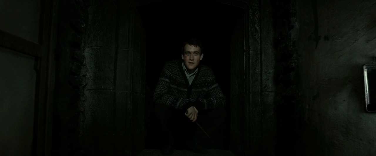 What is a Tritagonist? Definition & Film Examples 8 Neville Longbottom crouches in a dark stone passageway, holding a wand.
