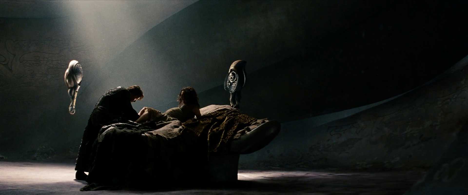 What Is a Backstory in Film? Definition & Famous Examples 5 A dimly lit alien room with carved stone walls and two hovering machines. A man kneels beside a woman giving birth on a futuristic bed.