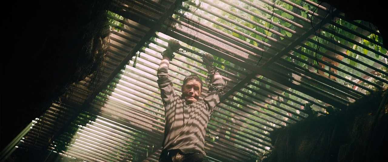 What does In Medias Res Mean? Definition & Examples from Film 2 Max hangs by his chained wrists under a slatted roof, with striped light cutting across his face and shirt. His mouth is gagged, and vines and foliage cling to the ceiling above him.