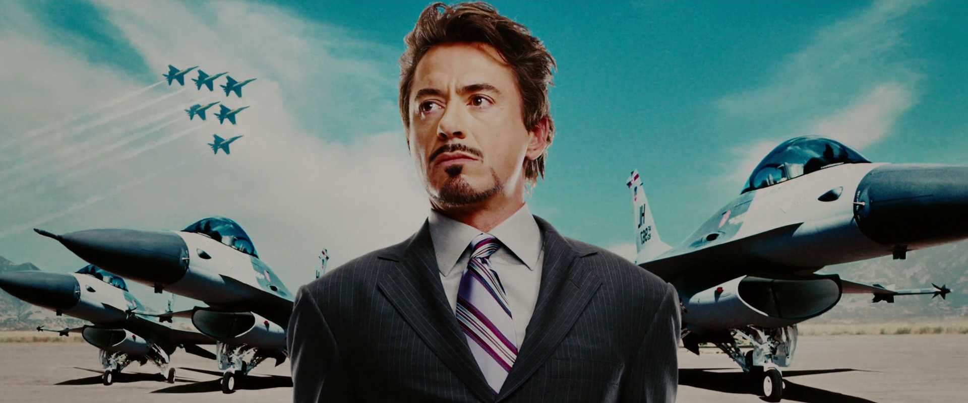 What is a Dynamic Character? Definition & How to Write One 2 Tony Stark in a dark suit and striped tie stands in front of fighter jets on a runway, with more jets flying in formation in the sky.