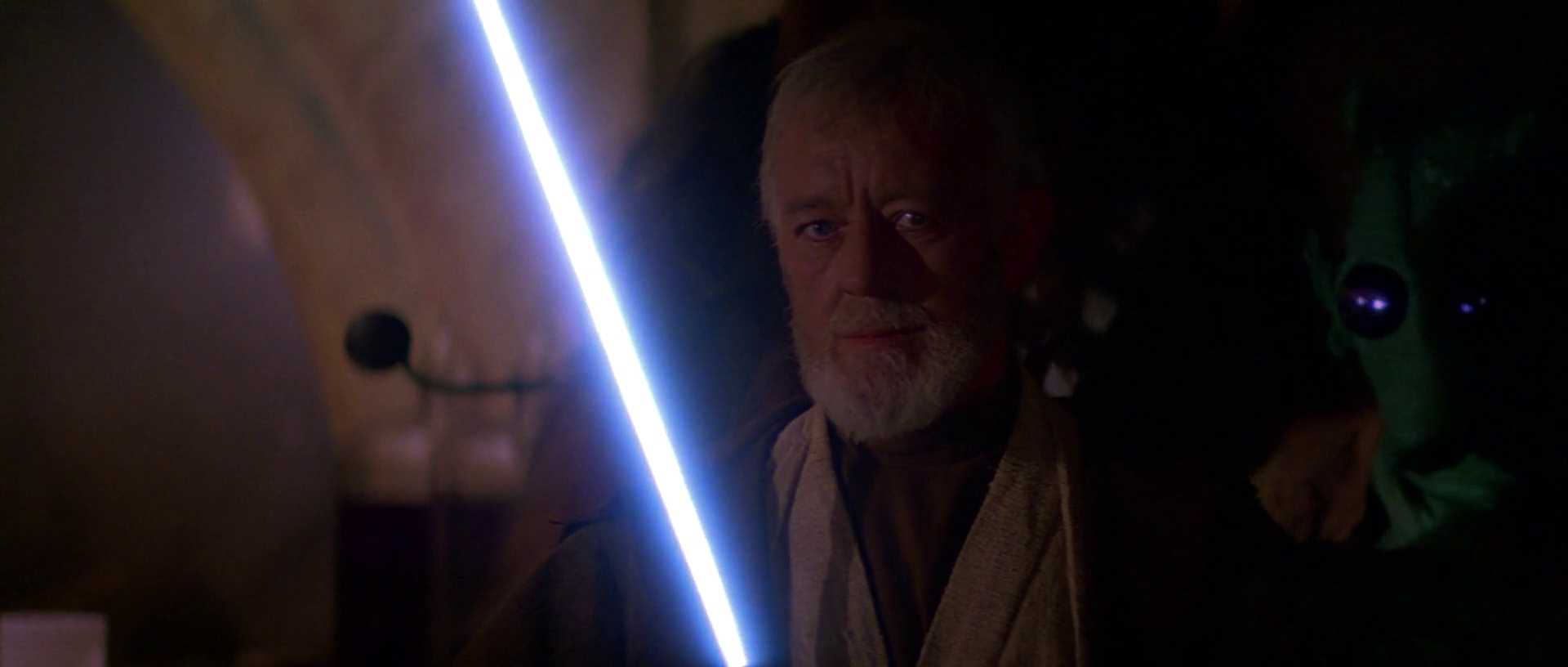 What is a Static Character? Definition & Film Examples 2 Close-up of Obi-Wan Kenobi holding an ignited blue lightsaber in a dim room, looking forward with a calm, focused expression.