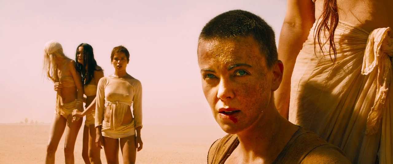 What is Characterization? Elements Defining Your Characters 16 Furiosa, with a shaved head and dusty face, looks forward in the desert while other women stand behind her in pale clothing.