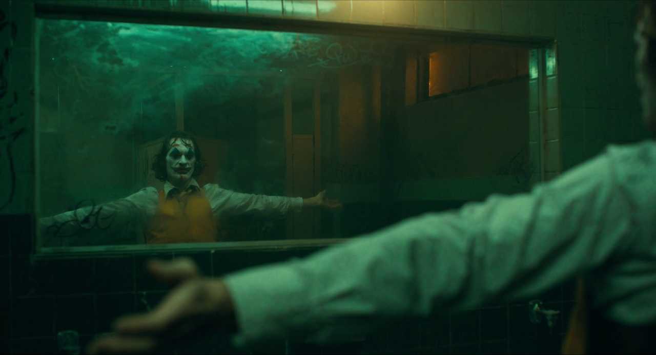 What is Characterization? Elements Defining Your Characters 14 Arthur, wearing clown makeup and a yellow vest, holds his arms out in front of a bathroom mirror under greenish light.