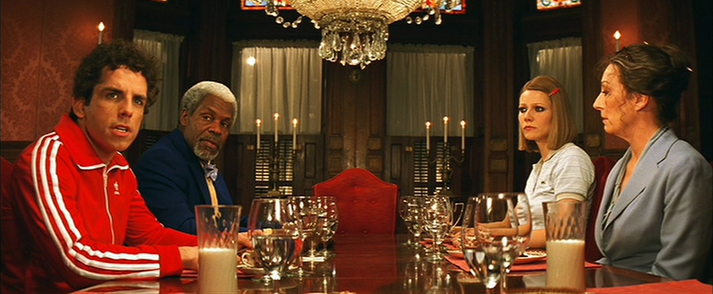Guide: Best Wes Anderson Movies (For Filmmakers to Learn From) 11 Four characters sit at a long dinner table, surrounded by ornate decor, each facing forward in The Royal Tenenbaums