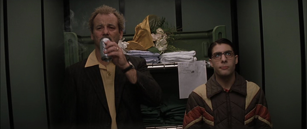 Guide: Best Wes Anderson Movies (For Filmmakers to Learn From) 10 Two characters stand in an elevator, one drinking a can and the other staring forward, in Rushmore