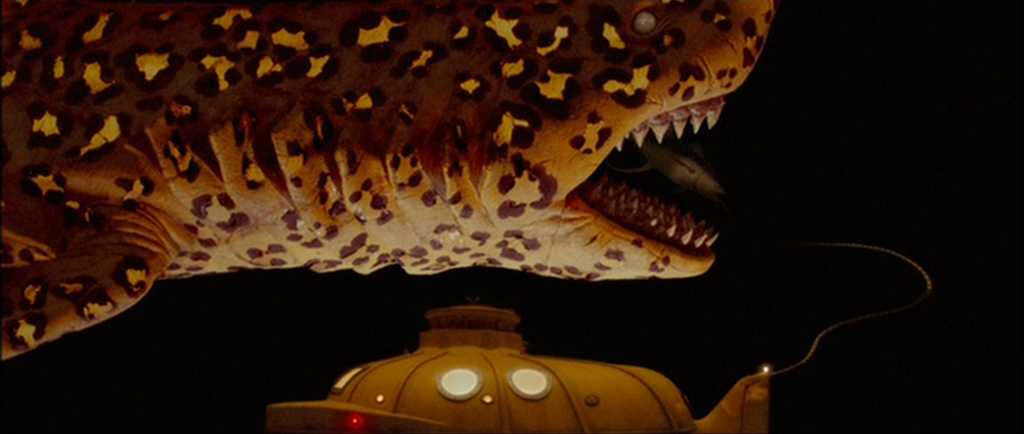 Guide: Best Wes Anderson Movies (For Filmmakers to Learn From) 4 A glowing yellow submarine floats beside a large stop-motion jaguar shark in the deep ocean in The Life Aquatic with Steve Zissou
