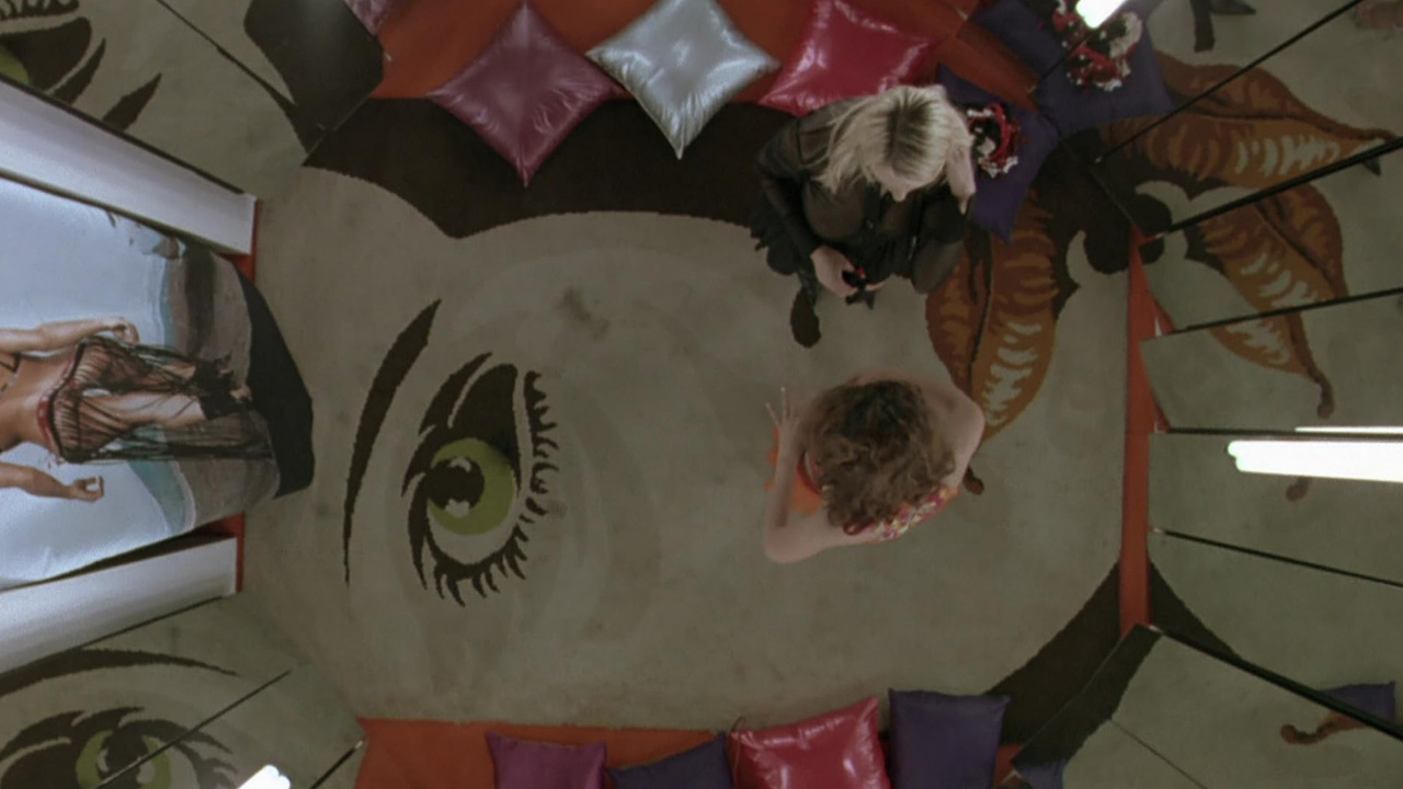 Sex, Power, and Rebellion: Symbolism in Tinto Brass Movies 2 Bird’s-eye view of two women in a mirrored room with a large eye painted on the floor