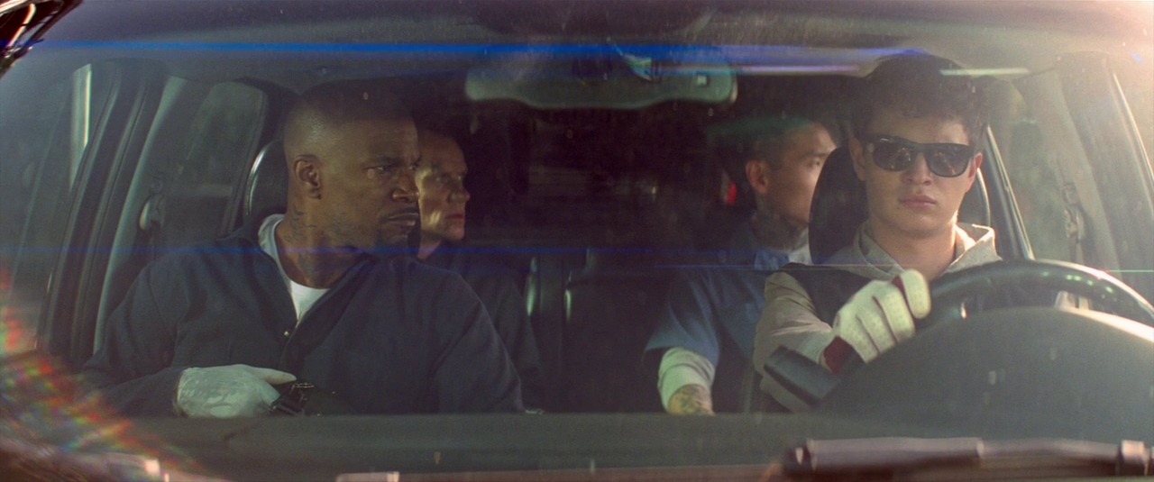 Rhythmic Editing: How Cut Timing Controls the Audience 2 A getaway driver wearing sunglasses sits behind the wheel with three tense passengers in Baby Driver
