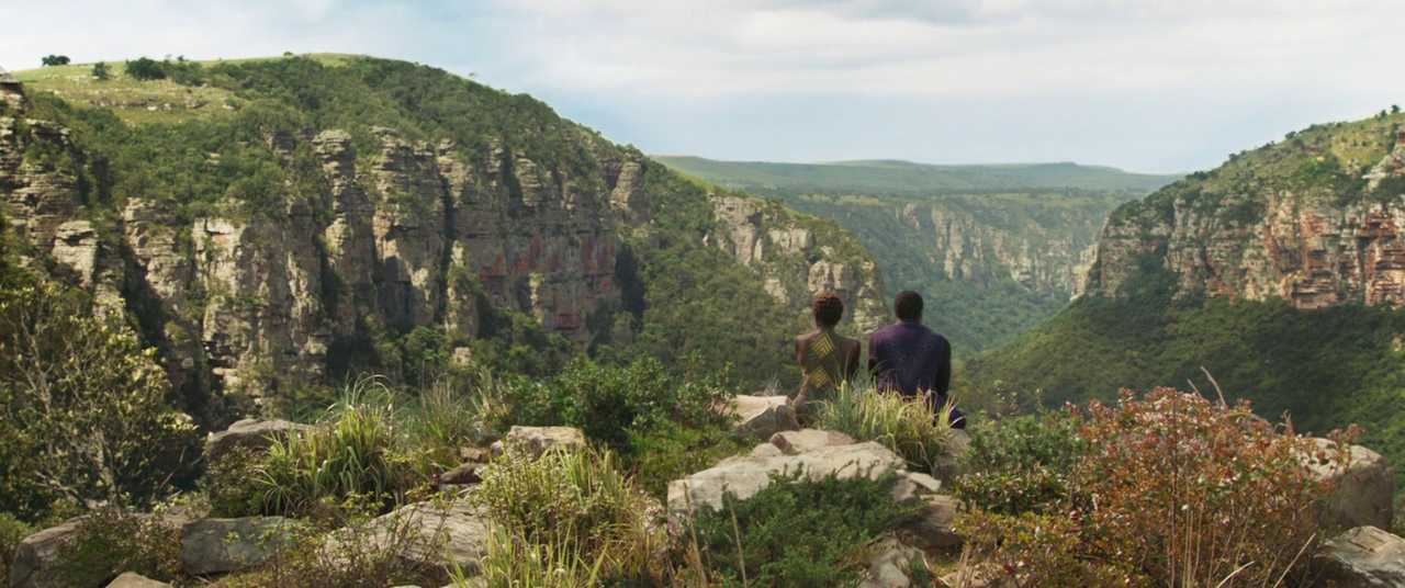 Film Theory: Definition, Discourses, and How to Use It 10 Two characters sit on a cliffside overlooking a lush, green valley in Black Panther