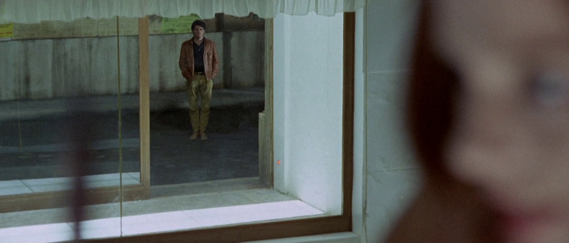 What Are Giallo Films? Definition, History & Key Examples 8 A woman watches two men through a glass window in a key mystery scene from The Bird with the Crystal Plumage (1970)