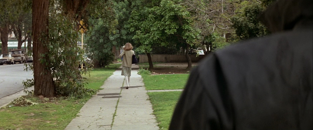 What Is a Horror Movie? Definition, Subgenres & Examples 6 Woman walking on sidewalk with masked figure watching from behind