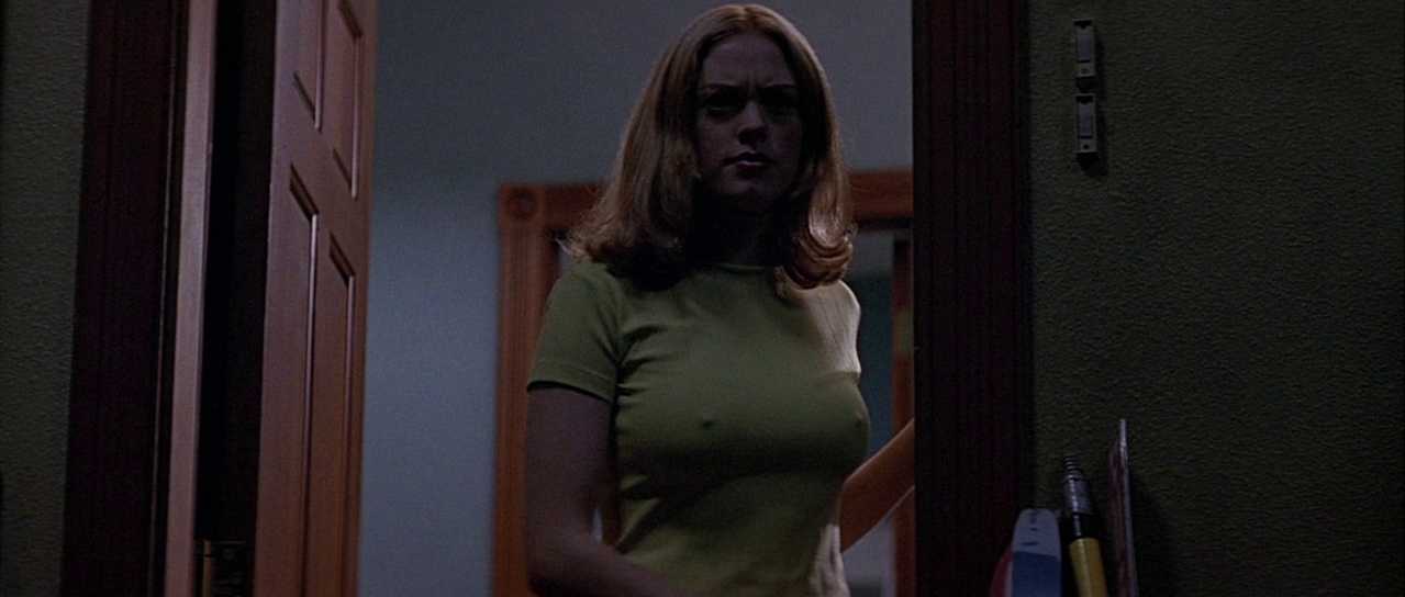 What Is Postmodernism? Definition, Key Traits & Film Examples 6 A young woman in a yellow shirt stands in a doorway, lit dimly from behind