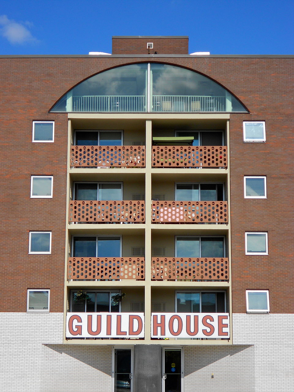 What Is Postmodernism? Definition, Key Traits & Film Examples 2 A brick apartment building with decorative gridded balconies and a bold sign reading "GUILD HOUSE"