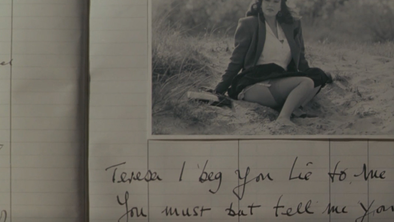 Sex, Power, and Rebellion: Symbolism in Tinto Brass Movies 8 Black-and-white photograph of a woman sitting on sand next to handwritten diary text, showing a mix of confession and desire in a personal journal.