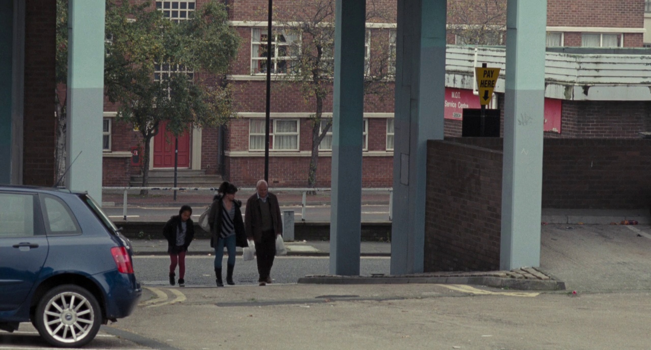 Film Theory: Definition, Discourses, and How to Use It 14 Still from I, Daniel Blake showing three characters walking under a concrete overpass in a working-class neighborhood