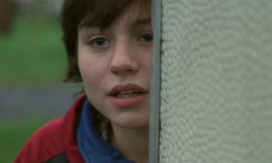 What Is Naturalism in Film? Realism, Lighting & Acting Explained 3 A close-up of a young woman peeking from behind a wall, looking tense and uncertain