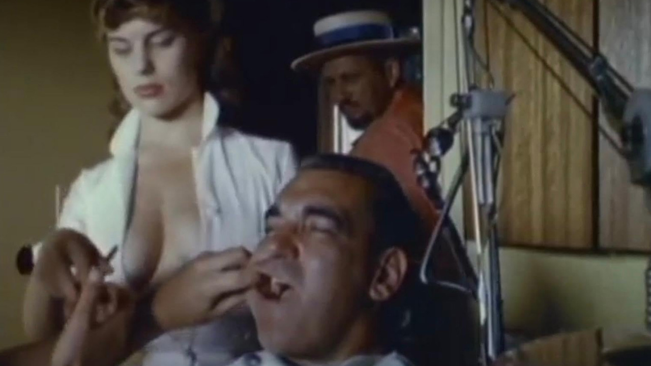 What Is Exploitation Cinema? Definition & Key Examples 4 Scene from The Immoral Mr. Teas showing a woman in a low-cut blouse and a man in a dentist chair reacting with amusement